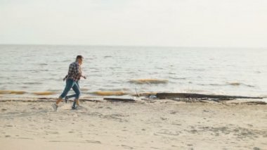 Yavaş hareket elele sahil çalışan bir adamla genç kız.