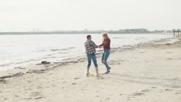 Cara e menina de mãos dadas rindo e girando na praia câmera lenta . — Vídeo de Stock