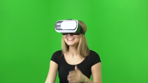 20s chica atractiva risa mientras se usa en gafas VR casco sobre un fondo de croma verde clave — Vídeo de stock