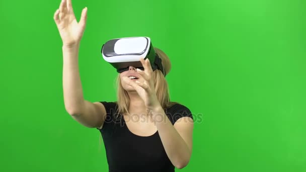 Mujer rubia de 20 años que se divierten, disfrutar de usar casco gafas VR sobre un fondo verde — Vídeo de stock