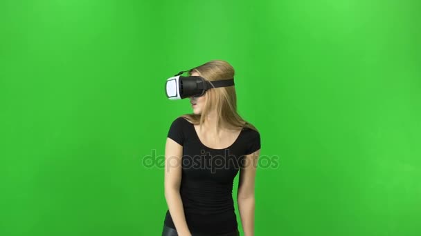 La mujer rubia de 20 años que usa gafas VR está mirando a su alrededor y concentrada. fondo clave croma verde — Vídeo de stock