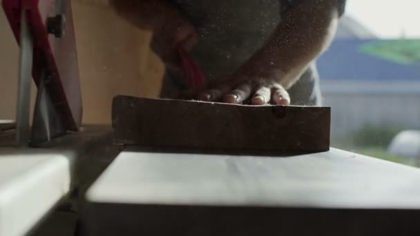 Mains de charpentier poussant la planche de bois sur la caméra à la machine à bois — Video