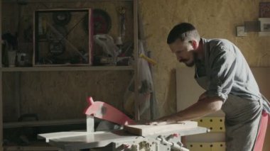 Woodworker ahşap tahta ile onun atölyesinde çalışıyor. güneşli gün