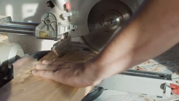 Feche as mãos de carpinteiro neg prancha de madeira usando serra circular. serragem voadora — Vídeo de Stock