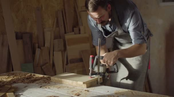 El carpintero barbudo de los años 20 trabaja con la máquina que golpea en el día soleado en taller — Vídeo de stock