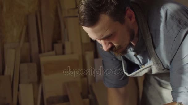 Retrato de 20s madeireiro barbudo usando máquina de escovar com prancha de madeira em sua oficina — Vídeo de Stock