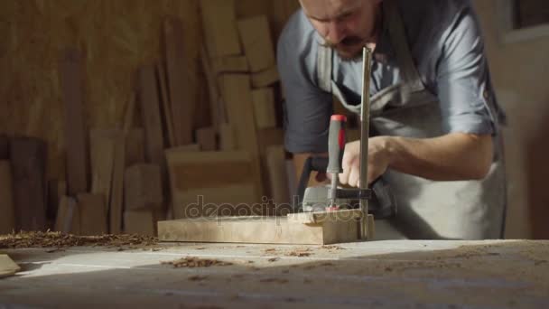 20'li yaşlarda woodworker işleri brashing makine ile güneşli gün atölyede sakallı — Stok video