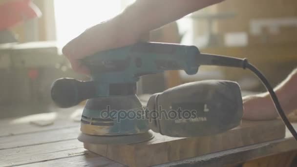 Hands of woodworker carpenter grinding wooden plank in backlight using machine — Stock Video