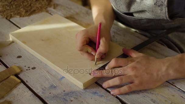 Close up hands of carpenter drawing on the wooden plank on table — Stock Video