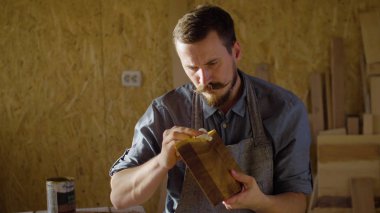 Marangoz woodworker elinde yakından bir ahşap tahta üzerinde cila losyonları