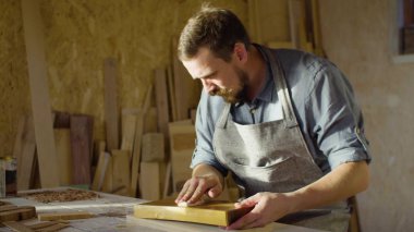 Marangoz woodworker elinde yakından bir ahşap tahta üzerinde cila losyonları