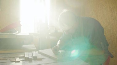 20'li yaşlarda adam marangoz ahşap tahta üzerinde çizim sakallı. güneşli bir günde atölye