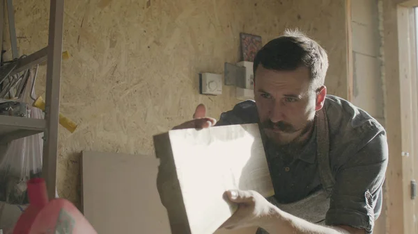 Konsantre woodworker portresi. 20'li yaşlarda iş onun atölyesinde makinede ahşap tahta ile marangoz