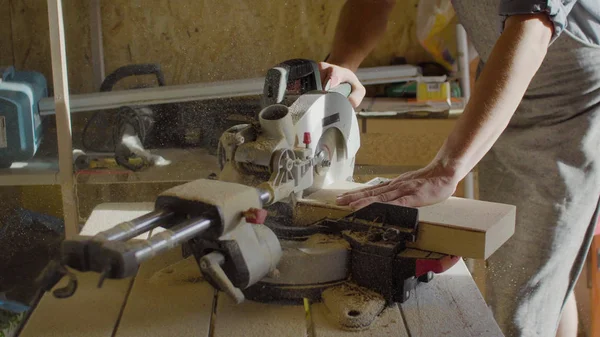 Cerca de las manos de carpintero tablón de madera neg usando sierra circular. aserrín volador — Foto de Stock