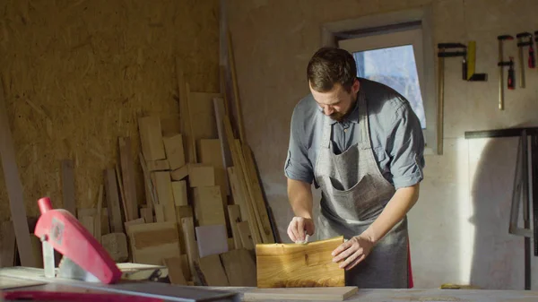 Retrato de carpintero barbudo años 20 carpintero carpintero frota laca en una plancha de madera en el taller — Foto de Stock