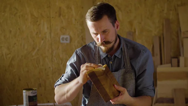 Marangoz woodworker elinde yakından bir ahşap tahta üzerinde cila losyonları