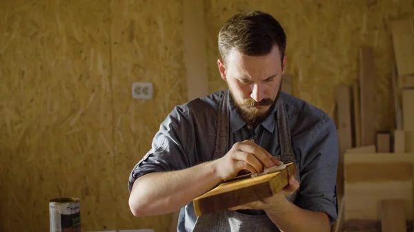 Cerca de las manos de carpintero carpintero frota laca sobre una plancha de madera — Foto de Stock