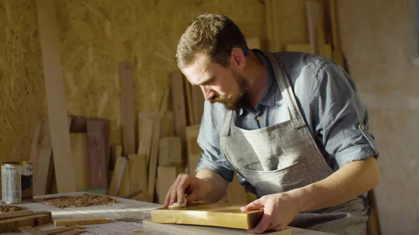 Marangoz woodworker elinde yakından bir ahşap tahta üzerinde cila losyonları