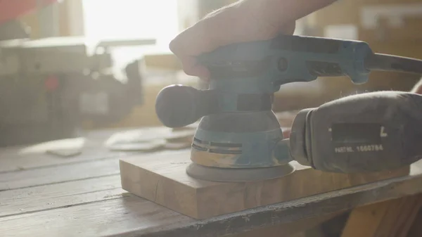 Manos de carpintero carpintero de madera moliendo tablón de madera en contraluz utilizando la máquina — Foto de Stock