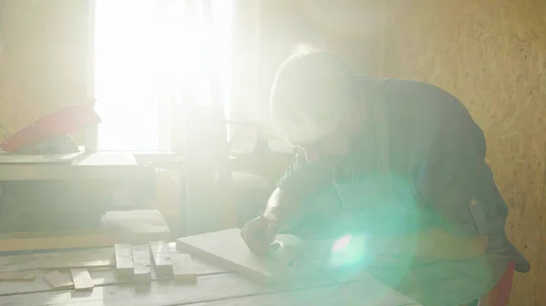 20'li yaşlarda adam marangoz ahşap tahta üzerinde çizim sakallı. güneşli bir günde atölye