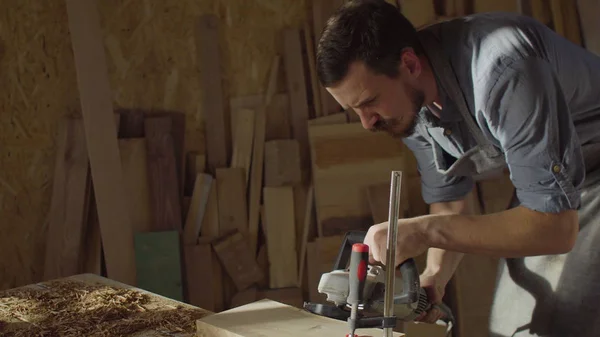 20s bearded woodworker works with brashing machine at sunny day in workshop Stock Picture