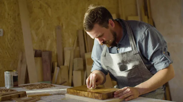 Hände eines Tischlers reiben Lack auf Holzplanke lizenzfreie Stockfotos