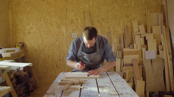 20s bearded carpenter drawing in workshop in sunny day Stock Picture