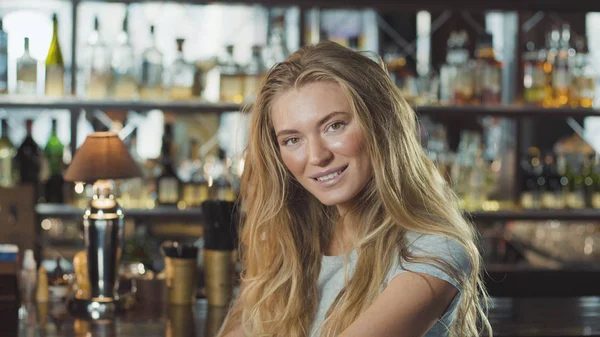 Abiye yakınındaki tezgahın oturuyor ve kameraya bakarak güzel sarışın kadın