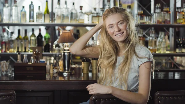 Abiye yakınındaki tezgahın oturuyor ve kameraya bakarak güzel sarışın kadın