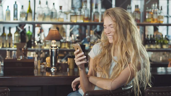 çekici kız bir barda oturmuş sayaç ile smartphone