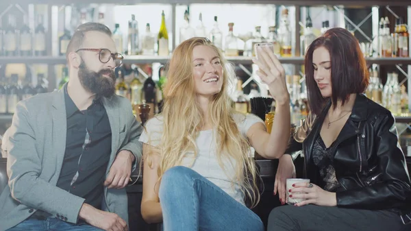gülümseyen ve smartphone kameraya mutlu duygular yüzler ile arıyorum arkadaş 3 kişi şirket sayaç, bar arkasında selfie alıyor
