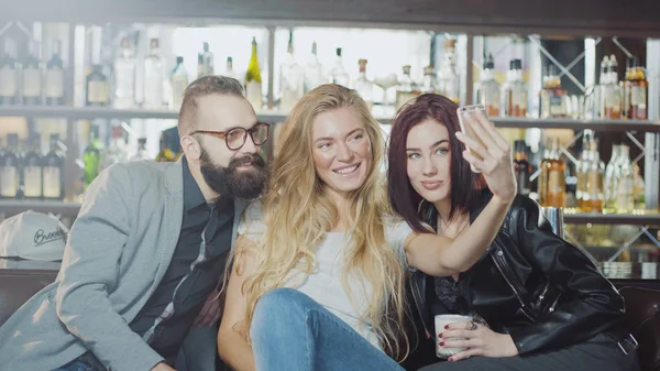 gülümseyen ve smartphone kameraya mutlu duygular yüzler ile arıyorum arkadaş 3 kişi şirket sayaç, bar arkasında selfie alıyor