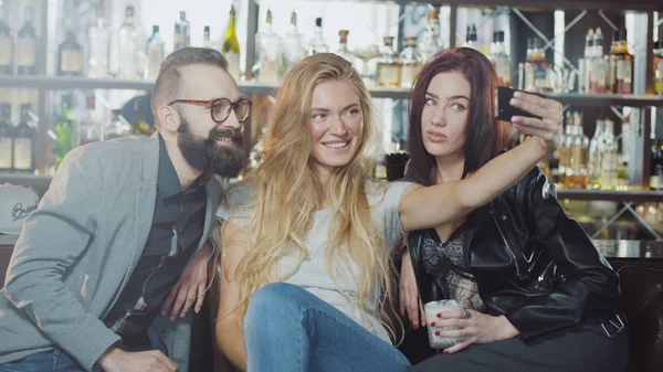 gülümseyen ve smartphone kameraya mutlu duygular yüzler ile arıyorum arkadaş 3 kişi şirket sayaç, bar arkasında selfie alıyor