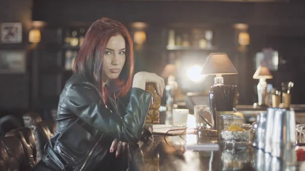20'li seksi güzellik Kızıl saçlı kadın siyah deri ceketli mi içki kokteyl, kamera ve flört gülümsüyor bardaki bakarak