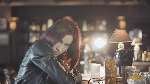 20'li seksi güzellik Kızıl saçlı kadın siyah deri ceketli mi içki kokteyl, kamera ve flört gülümsüyor bardaki bakarak
