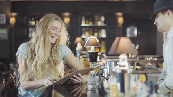 Бармен допомагає блондинці 20-х жінок зробити вибір в меню бар — стокове фото