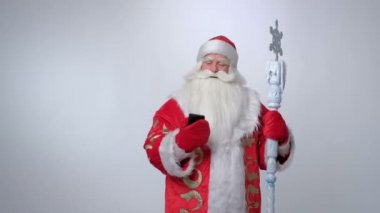 Mutlu Rus Noel Baba 'sı akıllı telefonuyla fotoğraf çekiyor ve gülümsüyor.