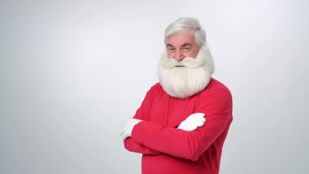 Portret van senior man in KERSTMUTS camera kijken en knipogen over licht grijze achtergrond — Stockvideo