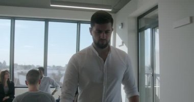 Resmi giysili esmer genç dalgın bir adam takımı terk ediyor.