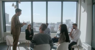 Resmi kıyafetli genç konuşmacı çok ırklı bir takıma