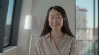 Ofiste poz veren güzel, gülümseyen Asyalı genç bir kadının portresi.