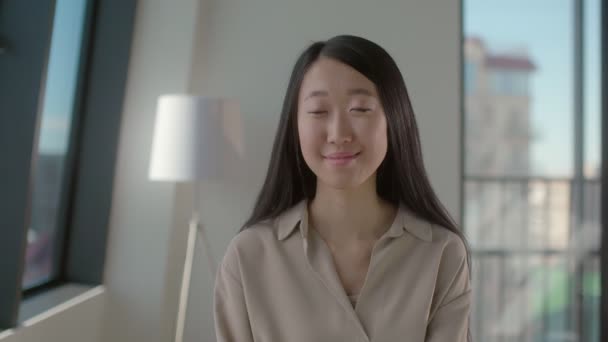 Портрет позитивной довольно улыбающейся азиатской молодой женщины, позирующей в офисе — стоковое видео
