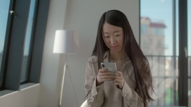 Όμορφη Ασιάτισσα που μιλάει στα κοινωνικά δίκτυα χρησιμοποιώντας ένα smartphone — Αρχείο Βίντεο