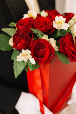 Elinde kırmızı güller olan bir adam.