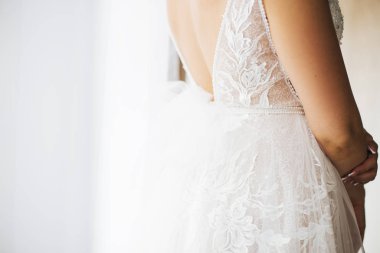 Gelin, ince dantelli bir gelinlik içinde ve sırtı açık bir şekilde evleniyor. Boşluğu kopyala.