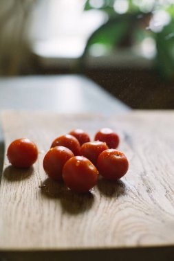 Olgun vişneli domatesler ahşap bir kesim tahtasının üzerinde, yazın kapalı alanda su damlalarının altında. Vejetaryen, vejetaryen, vejetaryen. Domatesli taze salata pişiriyorum.. 