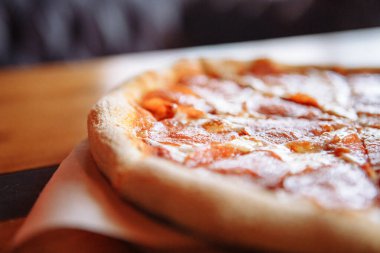 Samimi kafedeki ahşap masada pepperoni pizza.