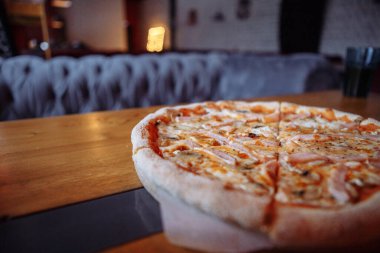 Sıcak bir kafede, ahşap bir masada taze pizza.