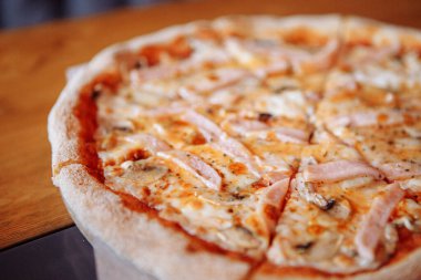 Sıcak bir kafede, ahşap bir masada taze pizza.