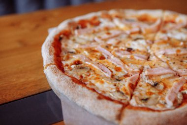 Sıcak bir kafede, ahşap bir masada taze pizza.